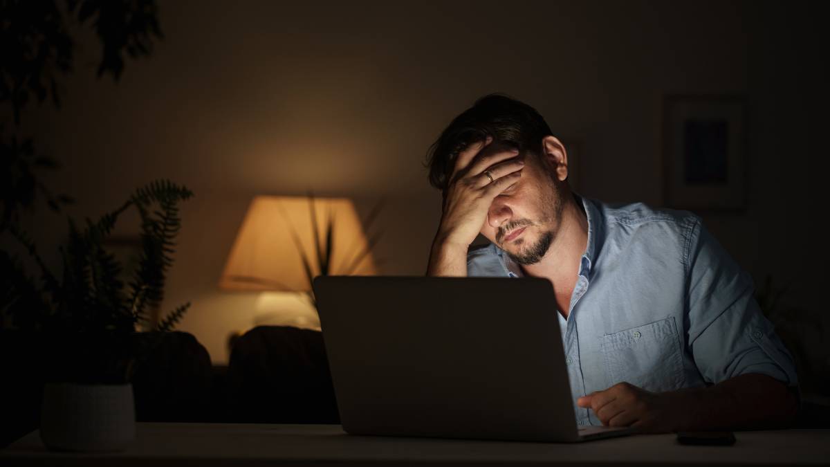 Man sitting at laptop looking stressed